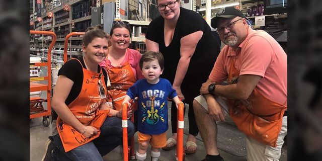 Two-year-old Logan Moore with some of the Home Depot employees who built his walker (Facebook/Jeffrey Anderson)