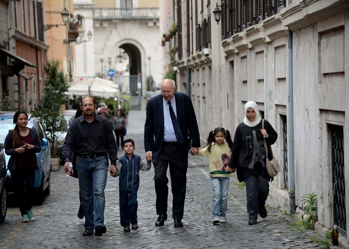 A family of Syrian refugees, part of a group of asylum seekers Pope Francis helped resettle, walks with a member of a Catholi