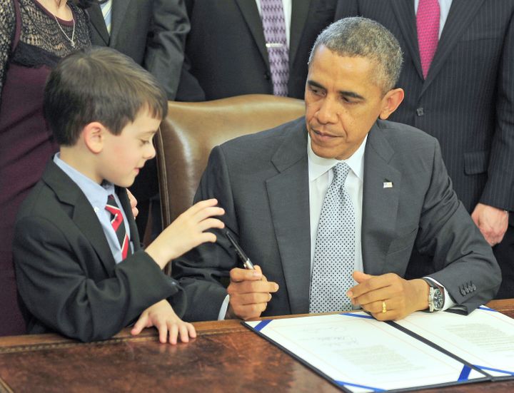 Obama presents a pen to Jacob Miller after signing legislation.
