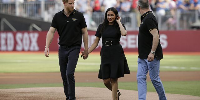 Britain's Prince Harry, left, and Meghan, Duchess of Sussex, walk off the field.