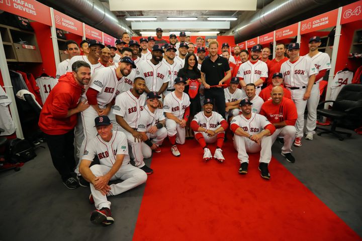 Meghan Markle and Prince Harry pose for a photo with the Red Sox in the clubhouse prior to the game.