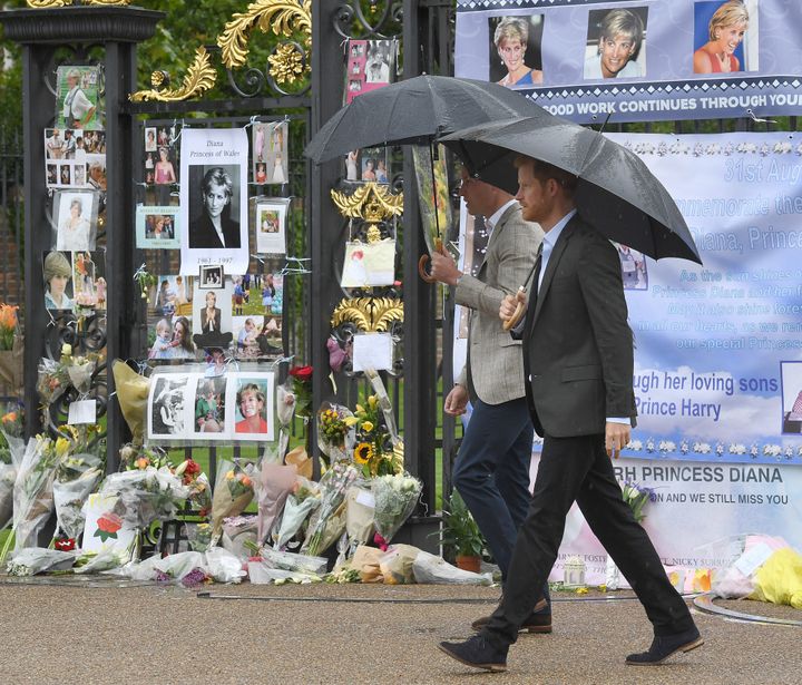William and Harry look at tributes left by the public dedicated to their mother Princess Diana following their visit The Whit