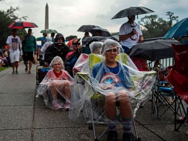 PHOTO: People cover from the rain as they gather on the National Mall ahead of the Salute to America Fourth of July event with President Donald Trump at the Lincoln Memorial in Washington, July 4, 2019.