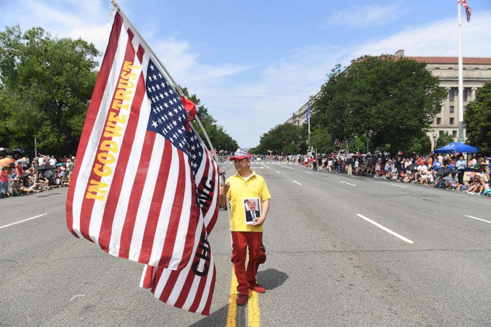 PHOTO: A man holding flags and a photograph of President Donald Trump marches in the Independence Day parade in Washington, D.C., July 4, 2019.