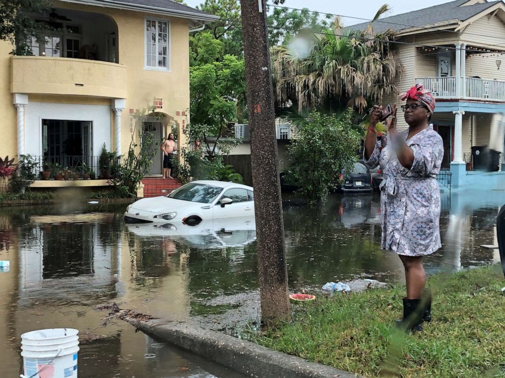 PHOTO: A woman stands photographing the scene in a flooded street in New Orleans, July 10, 2019.