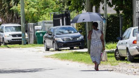 A woman uses an umbrella for shade as she walks on a hot day in Miami.