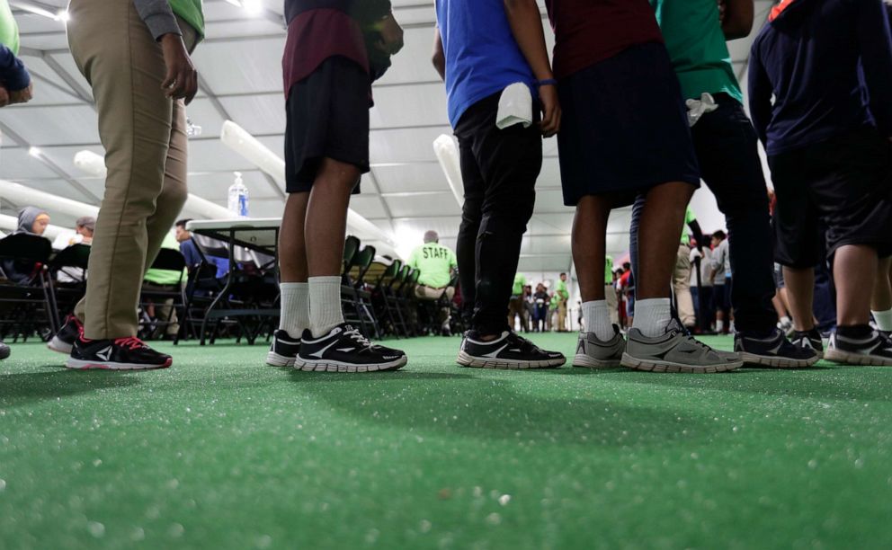 PHOTO: In this July 9, 2019 photo, immigrants line up in the dinning hall at the U.S. governments newest holding center for migrant children in Carrizo Springs, Texas.