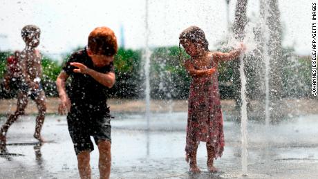 Children cool down by playing in a public fountain during the summer heat on July 19 in New York.