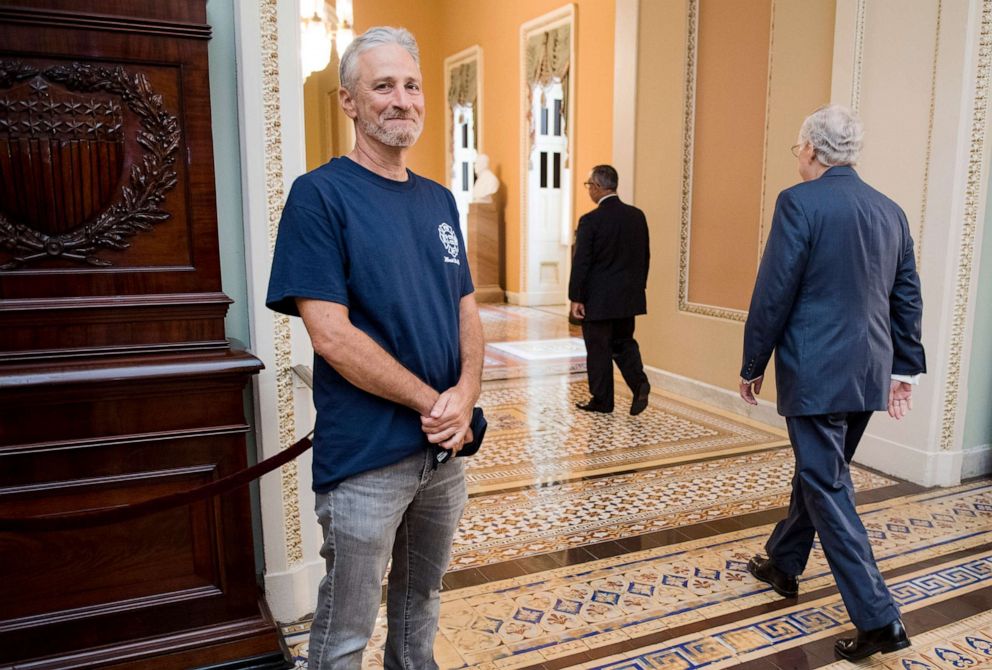 PHOTO: Jon Stewart, former host of The Daily Show, smiles as Senate Majority Leader Mitch McConnell walks by at the Ohio Clock Corridor in the Capitol, July 23, 2019.