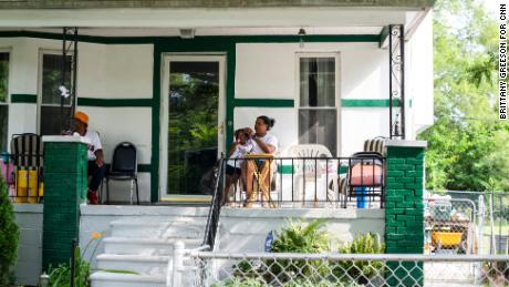 Crystal Daniels and her 3-year-old daughter, Mikayla Daniels, gaze out at passing cars while hanging out on their front porch with Crystal&#39;s father, Wayne Daniels, on the city&#39;s west side. Wayne has lived in the neighborhood for over 30 years.