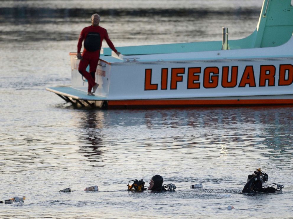 PHOTO: Divers emerge from the water as debris believed to be from a car floats to the surface, where a car went off a pier and into the water, in Los Angeles San Pedro harbor district, April 9, 2015.