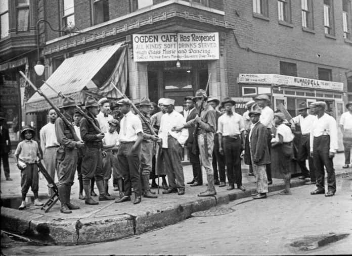 Crowd of men and armed National Guard in front of the Ogden Cafe during the race riots in Chicago, Illinois, 1919.