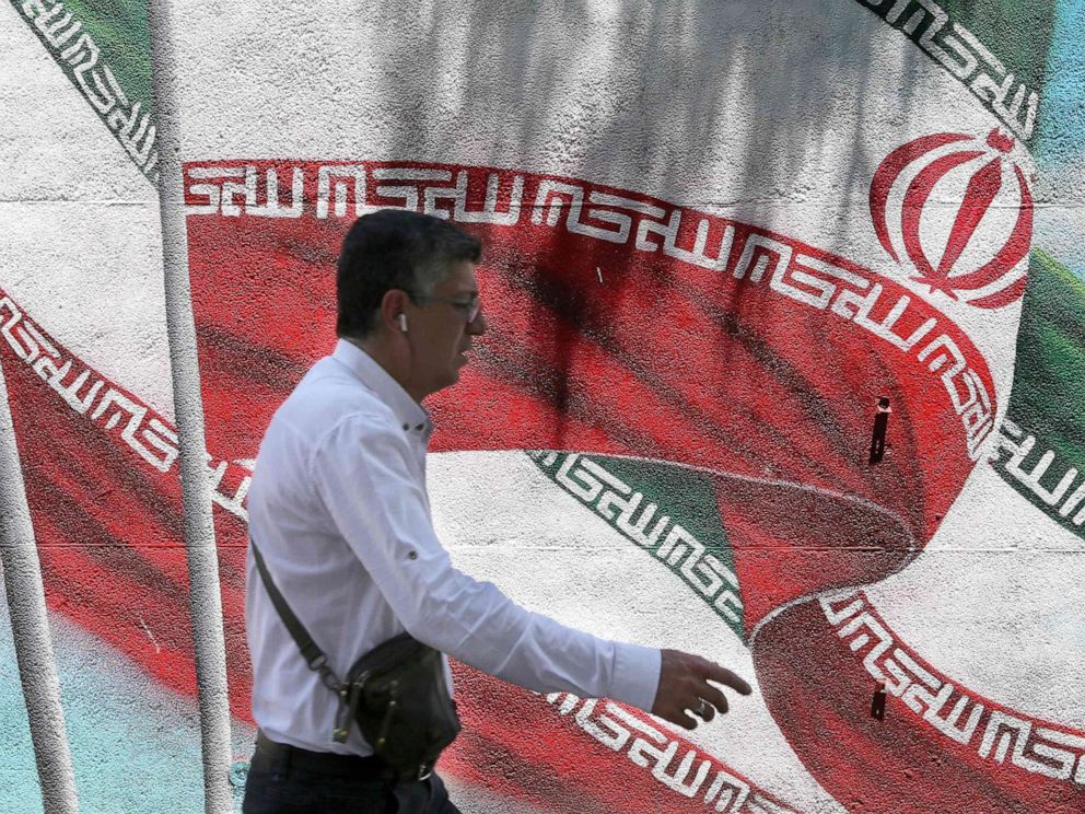 PHOTO: An Iranian man walks past a mural painted with the Iranian flag in Tehran on June 25, 2019. 