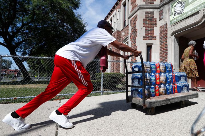 Teacher Cedric Cook pushes cases of water into Noble Elementary-Middle School in Detroit last year.