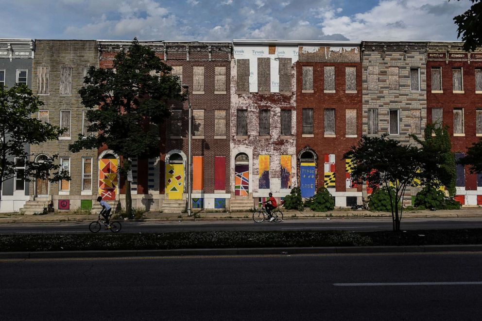 PHOTO: Young boys ride their bikes past boarded-up and abandoned row of houses in Baltimore, Maryland, U.S., May 26, 2019.