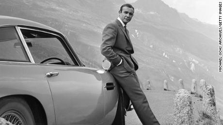 Actor Sean Connery poses as James Bond with his Aston Martin DB5 in a scene from the movie &#39;Goldfinger&#39; in 1964.