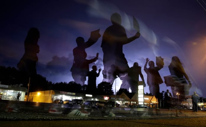 In this Aug. 20, 2014, file photo, protesters march in the street as lightning flashes in the distance in Ferguson, Mo. Michael Brown's death on Aug. 9, 2014, at the hands of a white Missouri police officer stands as a seismic moment of race relations in America. The fledgling Black Lives Matter movement found its voice, police departments fell under intense scrutiny, progressive prosecutors were elected and court policies revised. (AP Photo/Jeff Roberson, File)