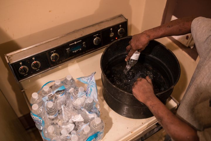 Flint resident Darryl Wilson, 46, empties a case of bottled water into a large pot to heat up for 45 minutes, allowing him to