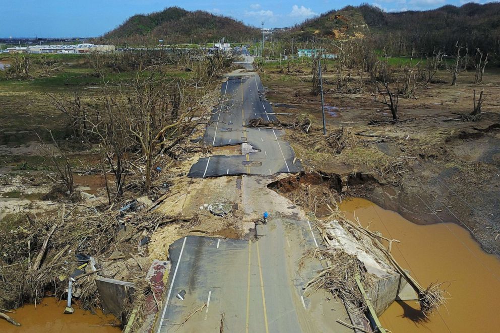 PHOTO: A man rides his bicycle through a damaged road in Toa Alta, west of San Juan, Puerto Rico, on September 24, 2017 following the passage of Hurricane Maria.