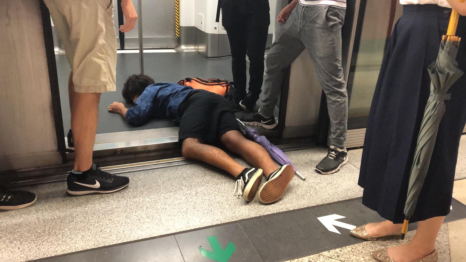 A protester lies on the floor, preventing the train from leaving in Hong Kong.