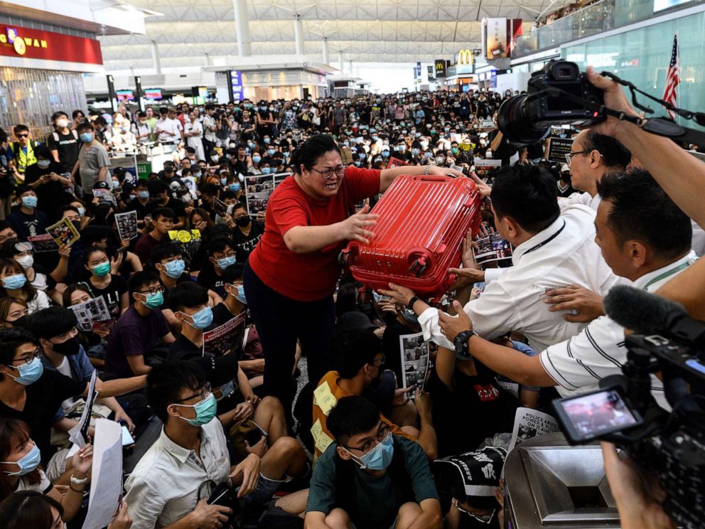 PHOTO: A tourist gives her luggage to security guards as she tries to enter the departures gate during another demonstration by protesters at Hong Kongs International Airport on Aug. 13, 2019. 