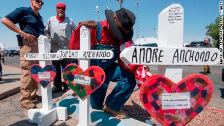 A man prays beside crosses bearing the names of Jordan and Andre Anchondo and the other victims of the El Paso massacre.
