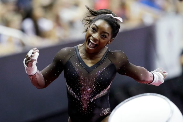 Simone Biles celebrates after competing in the uneven bars to win the all around senior women's competition at the 2019 U.S. Gymnastics Championships Sunday, Aug. 11, 2019, in Kansas City, Mo. (AP Photo/Charlie Riedel)