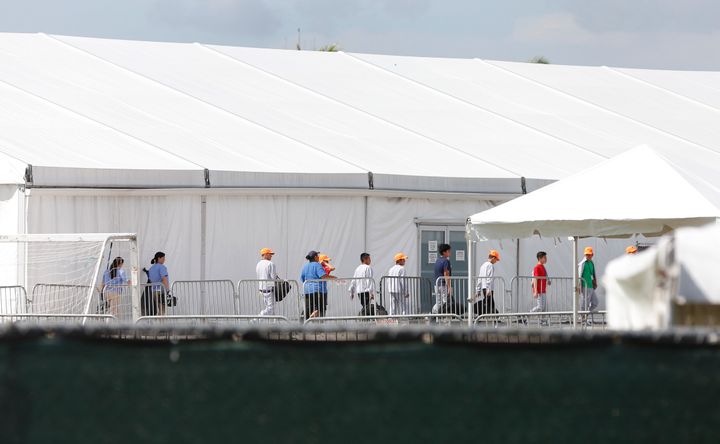 Migrant children separated from their families walk past tents at a detention center in Homestead, Florida on June 27, 2019. 