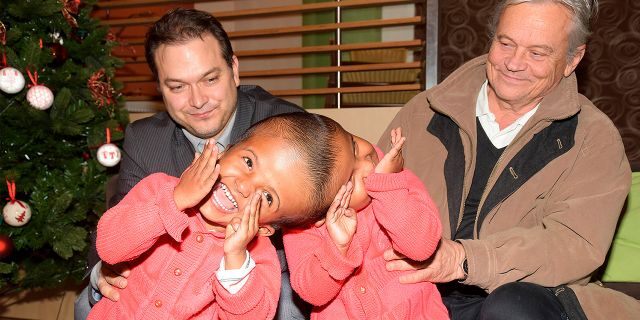 Hungarian doctors Gergely Pataki, left, and Andras Csokay pose together with Rabeya and Rukaya, two Bangladeshi girls who were born conjoined at the head in Budapest, Hungary. (Miklos Bemer/Action for Defenceless People Foundation via AP)