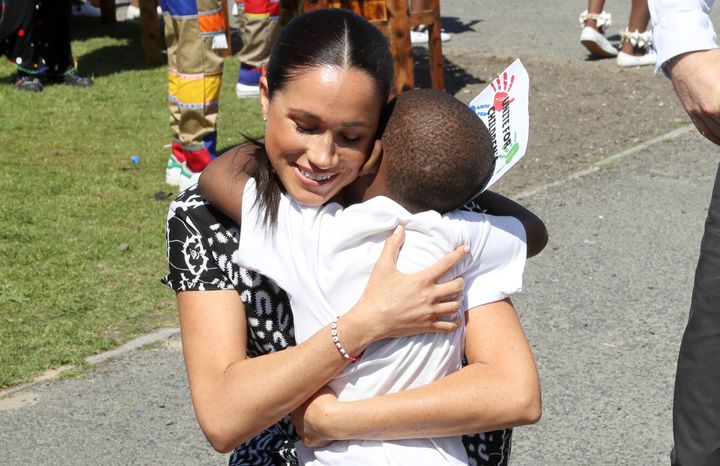 Meghan receives a hug from a young wellwisher as she visits a Justice Desk initiative in Nyanga township with Prince Harry.