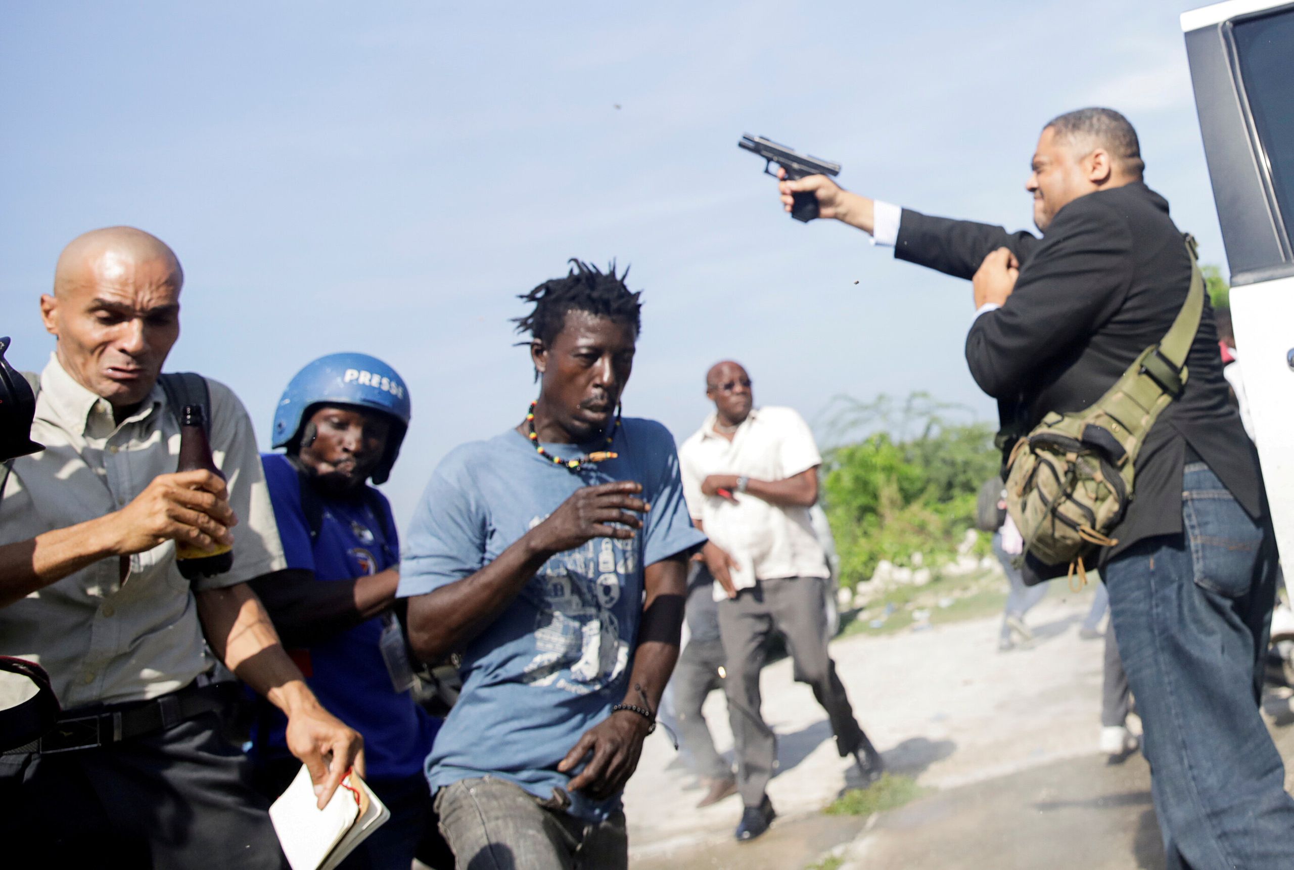 People run as Haiti's Senator Jean Marie Ralph Fethiere (PHTK) fires a gun in the air, injuring Chery Dieu-Nalio, a photograp