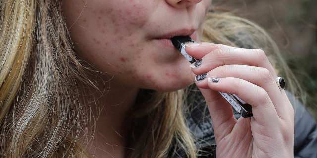 FILE - In this April 11, 2018, file photo, an unidentified 15-year-old high school student uses a vaping device near the school's campus in Cambridge, Mass. (AP Photo/Steven Senne, File)