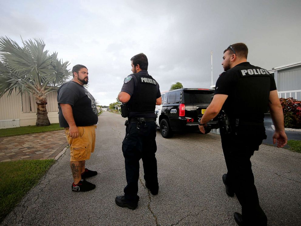 PHOTO: Vero Beach police officers talk to resident Todd Dufresne, left, as they notify residents of a trailer park community of a mandatory evacuation, in preparation for Hurricane Dorian, in Vero Beach, Fla., Sept. 2, 2019.