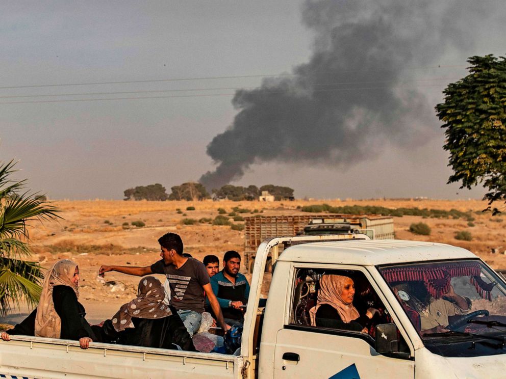 PHOTO: Civilians ride a pickup truck as smoke billows following Turkish bombardment in the northeastern town of Ras al-Ain in Syrias Hasakeh province along the Turkish border on Oct. 9, 2019.