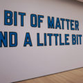A lovely text-on-wall work in blue by Lawrence Weiner reads, A BIT OF MATTER / AND A LITTLE BIT MORE.