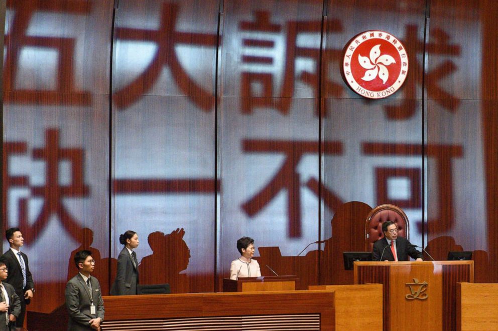 PHOTO: The words Five demands, not one less are projected onto the wall behind Hong Kongs Chief Executive Carrie Lam (2-R) as she arrives to deliver her annual policy address at the Legislative Council in Hong Kong on Oct. 16, 2019.