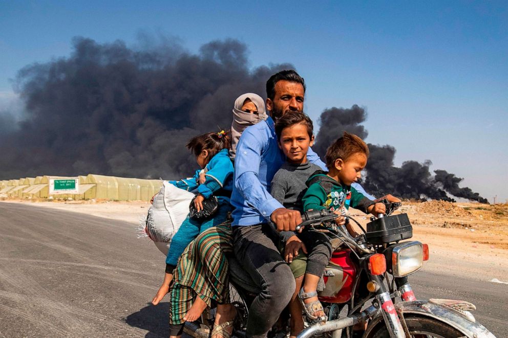 PHOTO: Displaced people, fleeing from the countryside of the Syrian Kurdish town of Ras al-Ain along the border with Turkey, ride a motorcycle together along a road on the outskirts of the nearby town of Tal Tamr on Oct. 16, 2019.