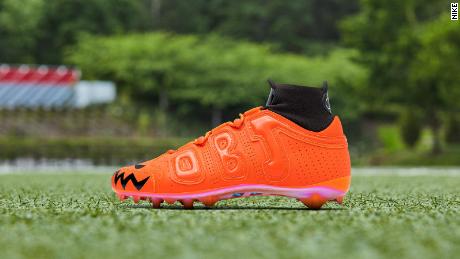 The neon orange cleat features Halloween-inspired designs.