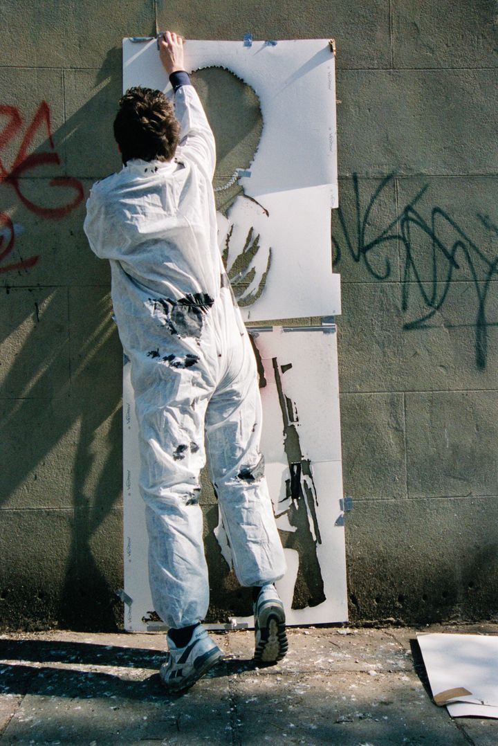 Banksy, pictured by Lazarides, putting up his "Pissing Guard" piece.