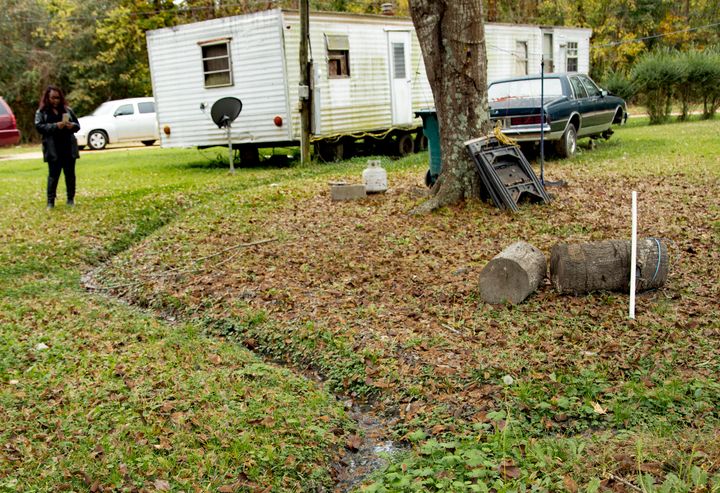 Environmental justice advocate Catherine Flowers examines an open sewer in the yard of a Lowndes County, Alabama, resident. R