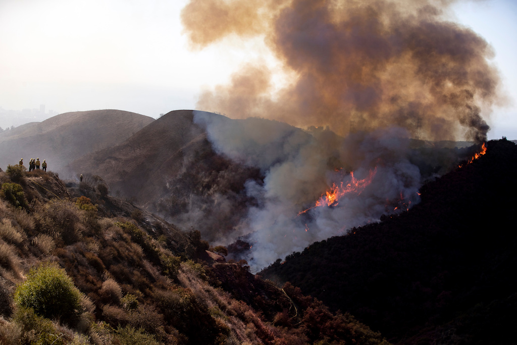 Firefighters look at the Getty Fire spreading in the hills behind the Getty Center in Los Angeles, California