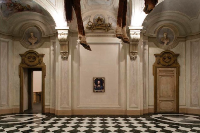 An image provided by the museum, of 'Salvator Mundi' accompanied by a detail of a hanging Maurizio Cattelan sculpture.