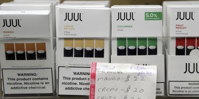 FILE - In this Thursday, Dec. 20, 2018 file photo, Juul products are displayed at a smoke shop in New York. On Thursday, Oct. 17, 2019, the company announced it will voluntarily stop selling its fruit and dessert-flavored vaping pods.