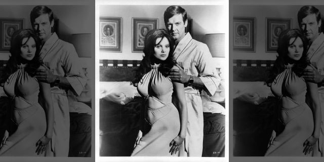 Madeline Smith leaning against Roger Moore in a suggestive manner as he touches her arm in a scene from the film "Live And Let Die," circa 1973.