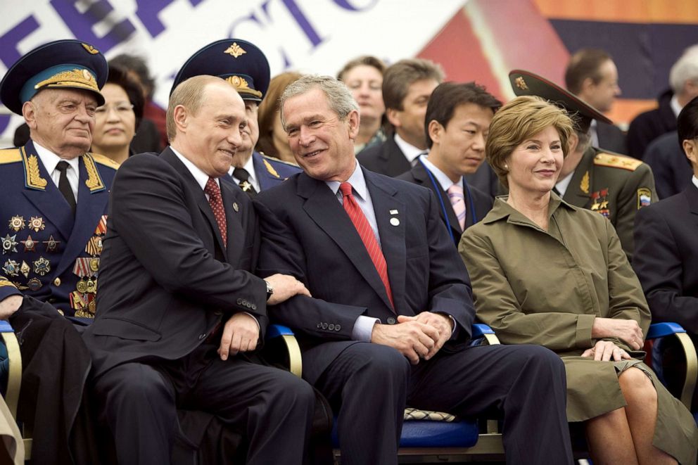 PHOTO: Former President George W. Bush, center, and Russian President Vladimir Putin, left, share a light moment as they sit with Laura Bush, right, and other heads of state during a military parade in Red Square in Moscow, May 9, 2005.