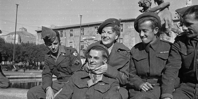 December 15, 1945: During an ENSA tour of Italy, singer and comedienne Gracie Fields (1898-1979) poses with members of the Allied Forces in Rome.