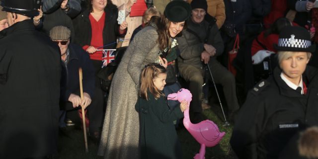 Britain's Catherine, Duchess of Cambridge, center left, speaks with her daughter Princess Charlotte as she holds a pink flamingo while greeting the public outside the St Mary Magdalene Church in Sandringham in Norfolk, England, Wednesday, Dec. 25, 2019. (AP Photo/Jon Super)