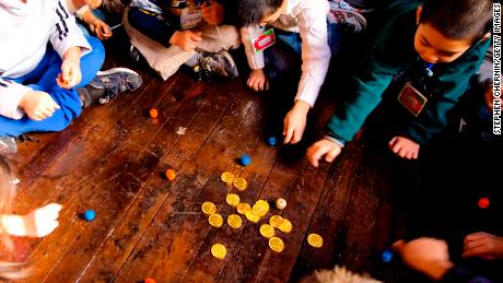 NEW YORK - DECEMBER 4:  PS 1 second grade students play with dreidels and chocolate gold coins after lighting the menorah December 4, 2007 at the Eldridge St. Synagogue in New York City. The class was there to learn about Hannukah and also about the newly restored synagogue which originally opened its doors in 1887.  (Photo by Stephen Chernin/Getty Images)