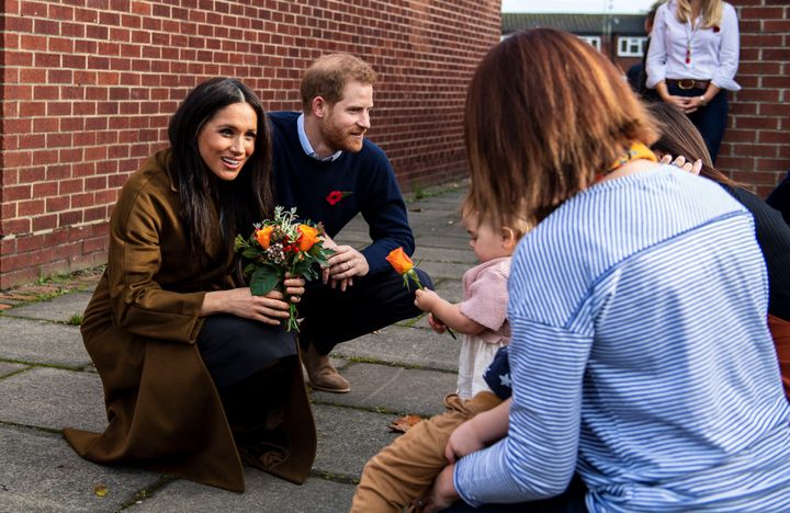 Bonnie and Maggie Emanuel give a posy of flowers to&nbsp; Meghan during a visit at Broom Farm Community Centre in Windsor on 