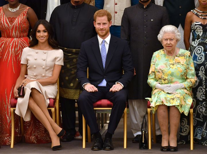 Queen Elizabeth, Prince Harry and the Duchess of Sussex pose for a picture with some of Queen's Young Leaders at a Buckingham